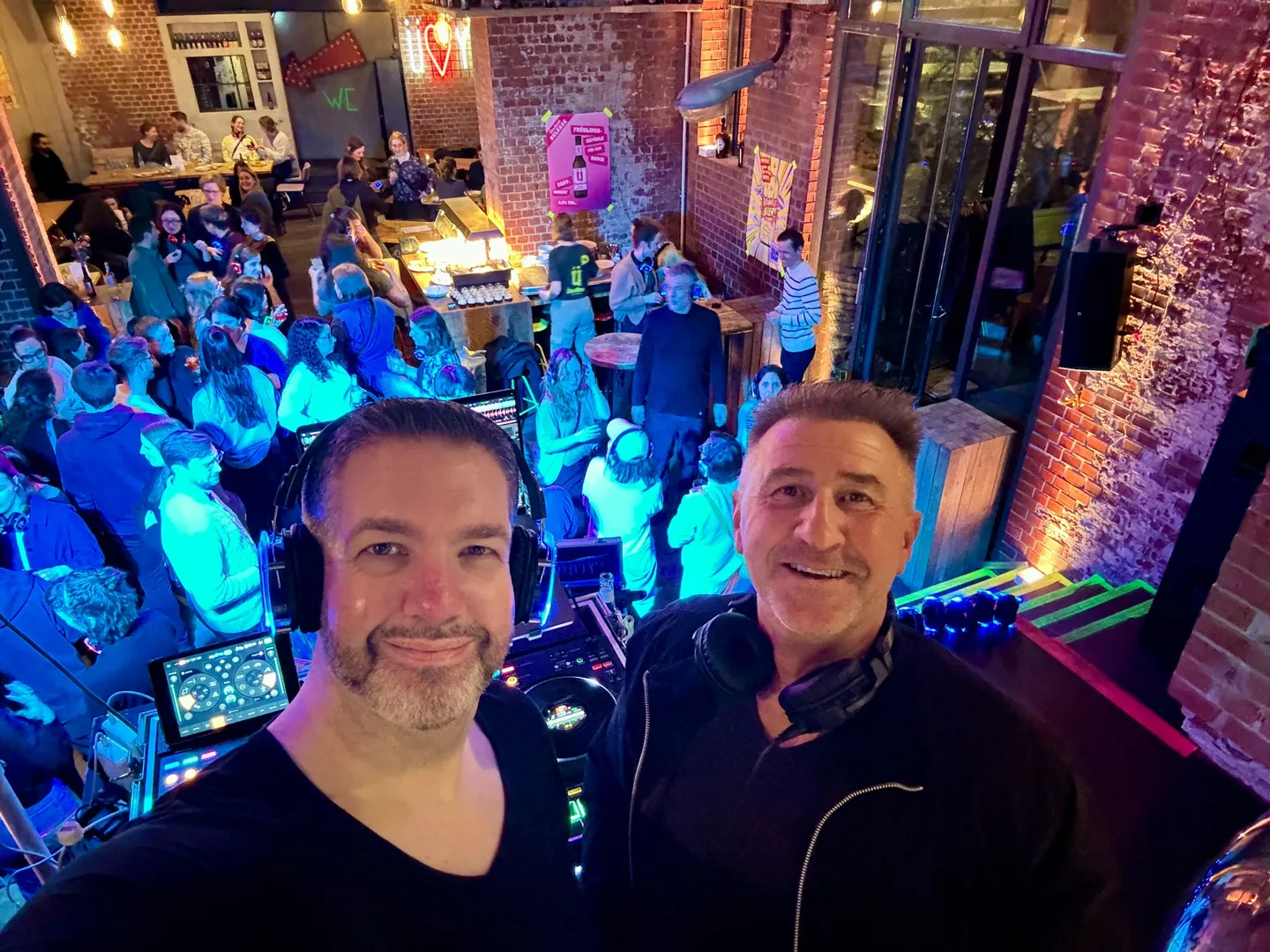 Silent-Disco-Feier mit DJs am Pult und Gästen mit leuchtenden Kopfhörern