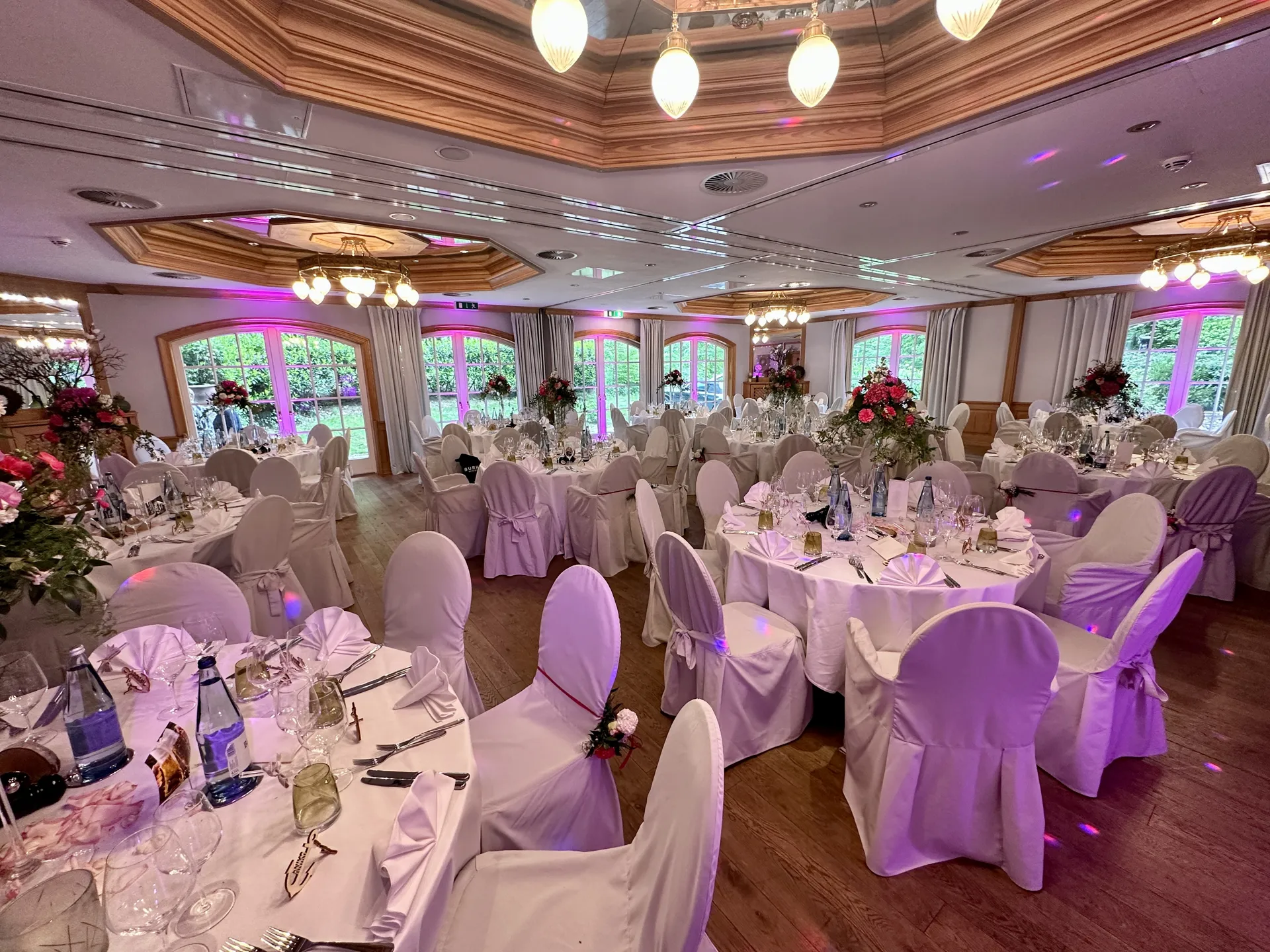 Festlich gedeckter Hochzeitssaal im Waldhaus Reinbek mit Kronleuchtern und farbigen Lichtakzenten