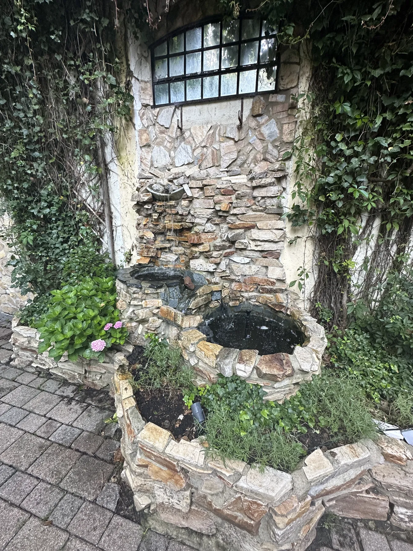 Steinbrunnen im grünen Außenbereich des Waldhauses Reinbek