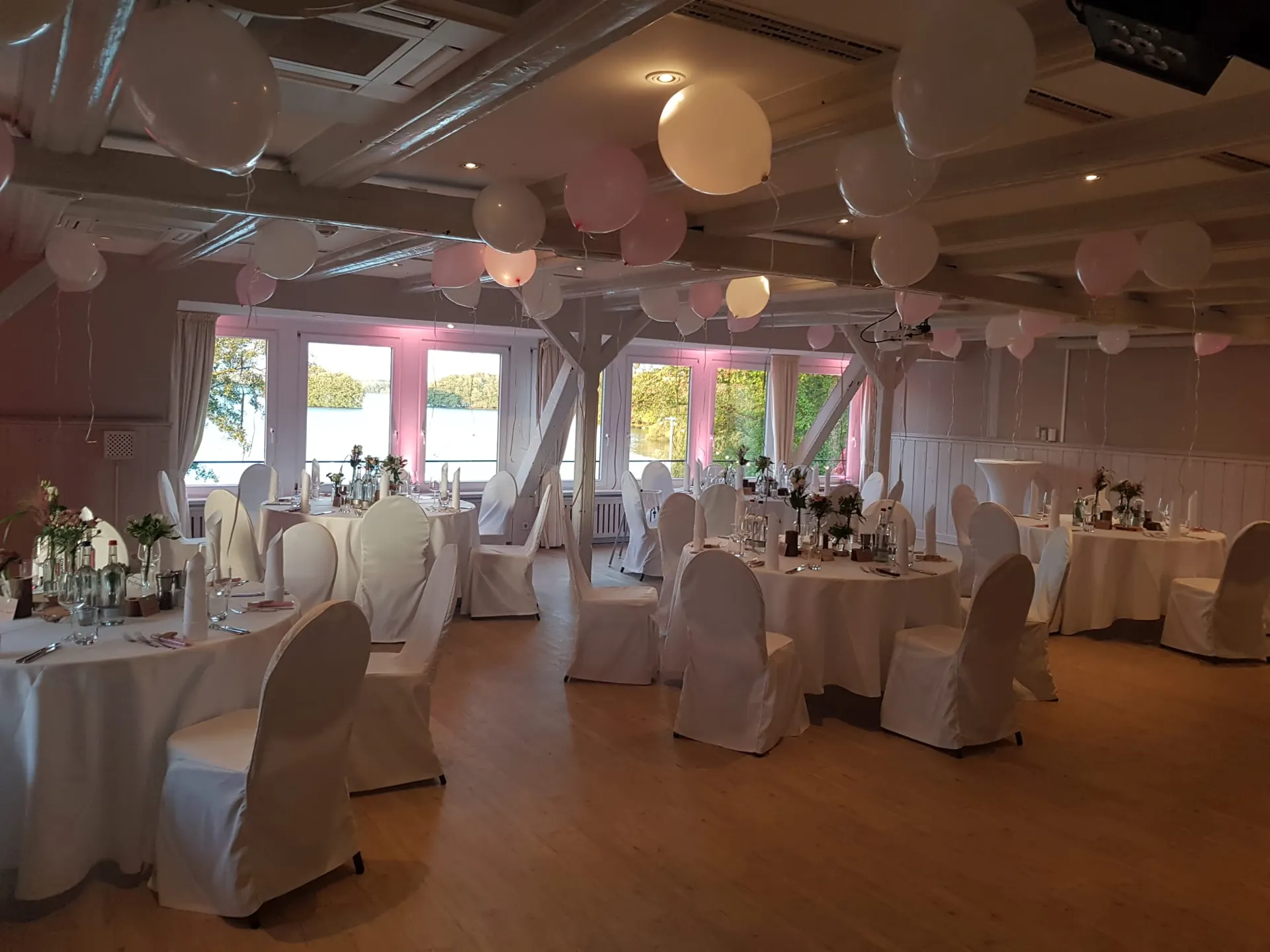 Hochzeitssaal mit runden Tischen und hängenden Lichtkugeln